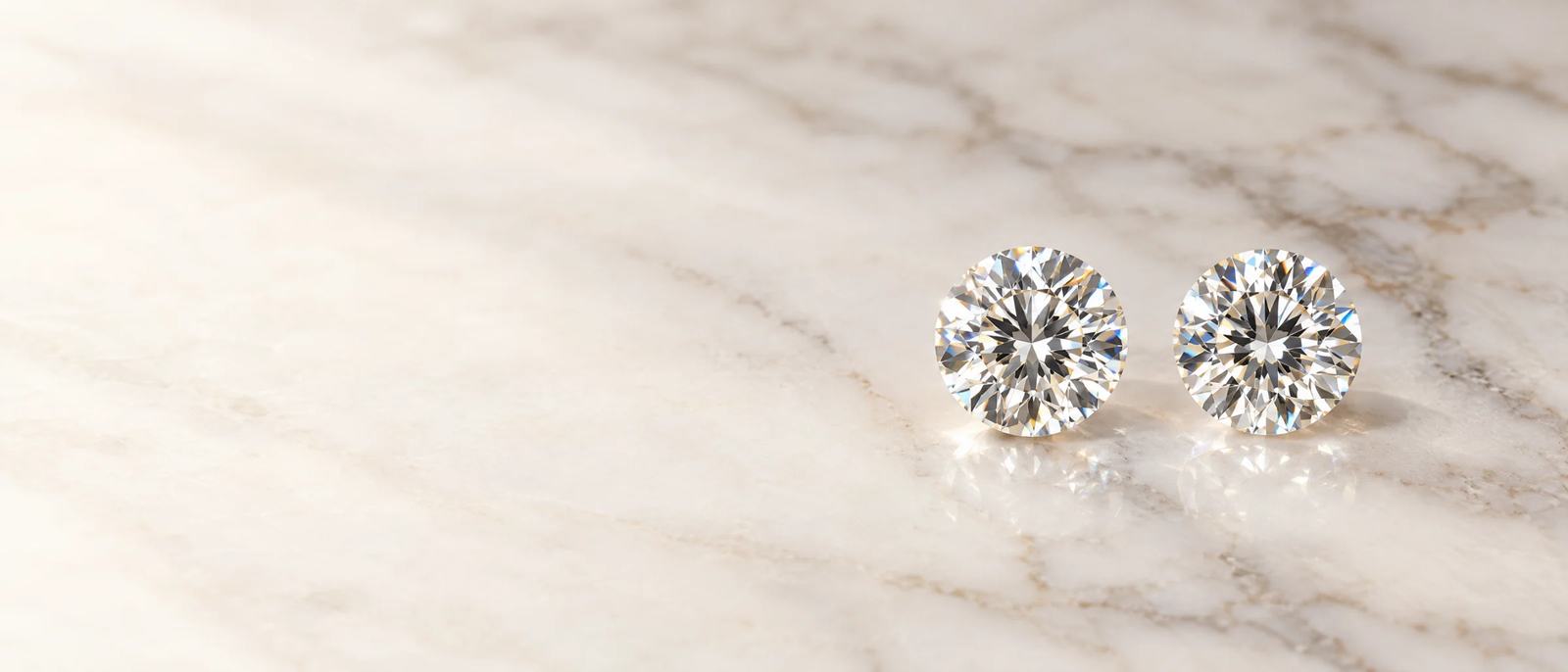 A natural diamond and a lab-grown diamond side by side on white marble
